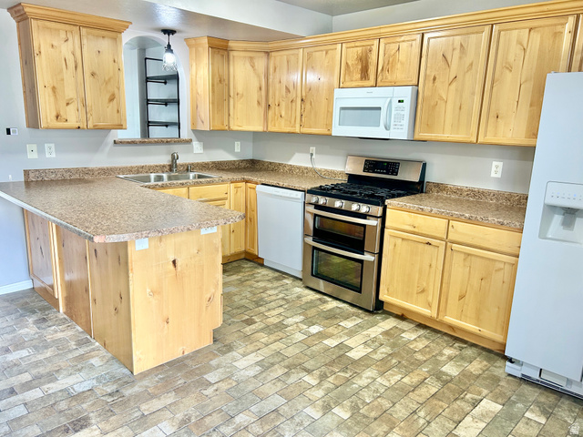 672 West 720 South Logan, UT 84321 - Photo 4 of 15 Kitchen featuring light wood cabinetry, stone-look countertops, and brick-patterned flooring