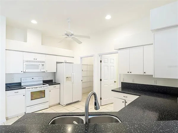 a kitchen with stainless steel appliances kitchen island a sink a stove and white cabinets