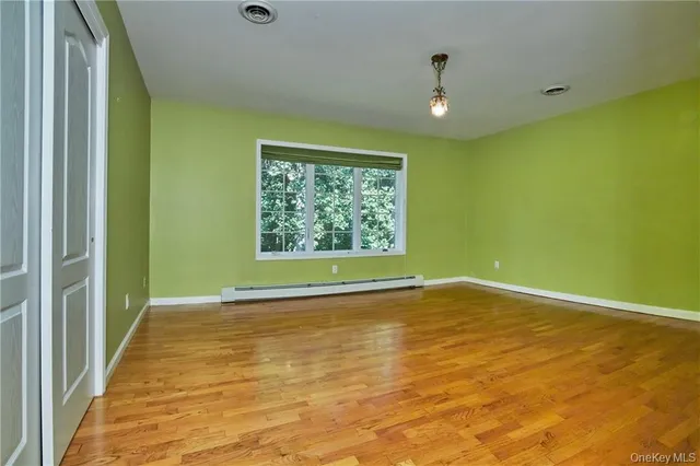 a view of an empty room with window and wooden floor