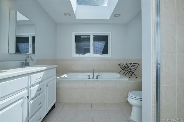 a bathroom with a granite countertop bathtub sink vanity mirror and toilet