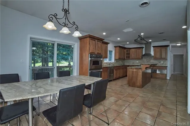 a kitchen with stainless steel appliances granite countertop a stove top oven a sink dishwasher a dining table and chairs with wooden floor