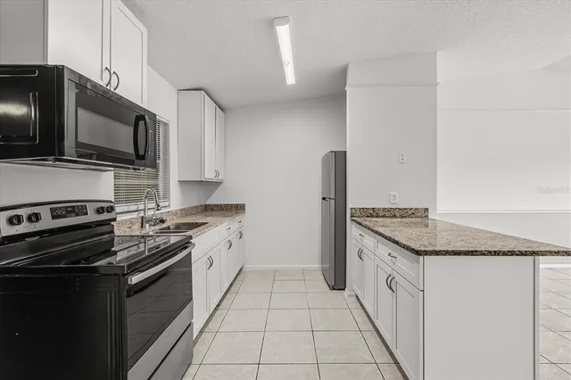 a kitchen with granite countertop a sink stainless steel appliances and cabinets