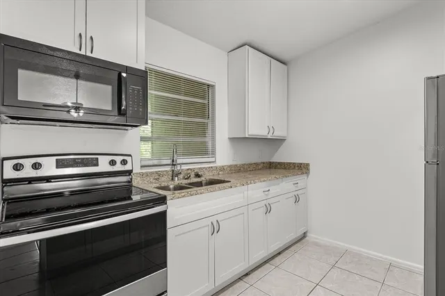 a kitchen with granite countertop a sink and a refrigerator
