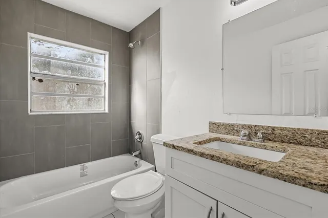 a bathroom with a granite countertop sink toilet mirror vanity and bathtub