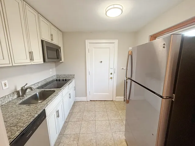 a kitchen with granite countertop a refrigerator and a sink
