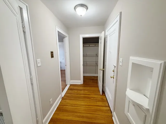 a view of a hallway with wooden floor and a bathroom