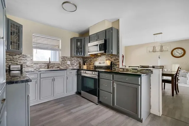 a kitchen with granite countertop a stove and white cabinets
