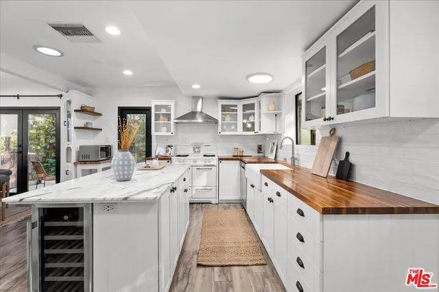 a large white kitchen with stainless steel appliances granite countertop a sink and cabinets
