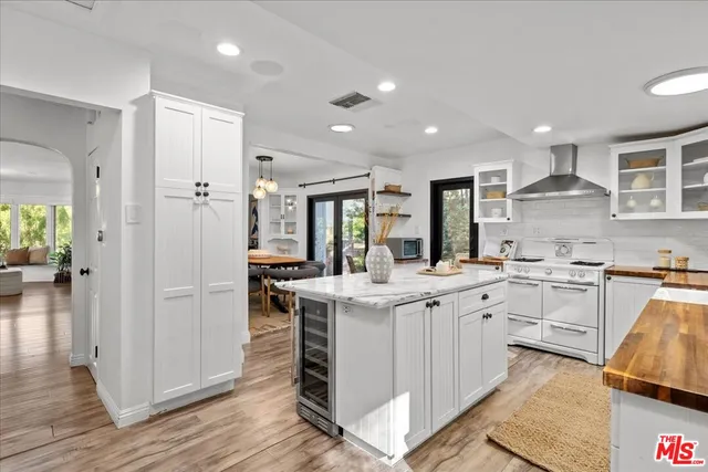 a kitchen with stainless steel appliances granite countertop a refrigerator a sink dishwasher and white cabinets with wooden floor