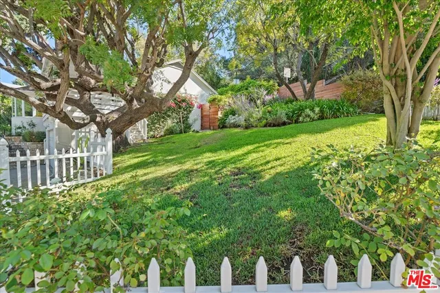 a view of a house with a small yard and large trees