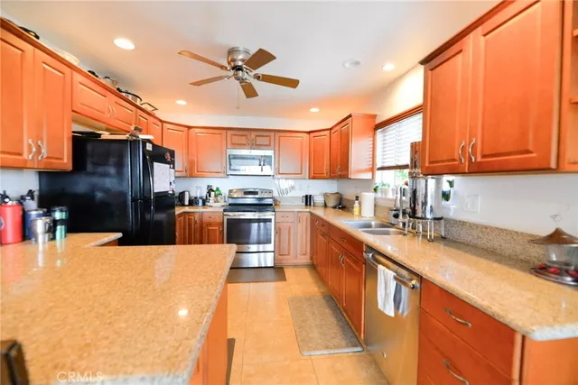 a kitchen with stainless steel appliances kitchen island granite countertop a refrigerator a stove top oven a sink with island and chairs