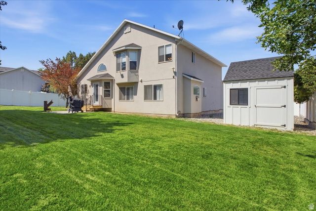 12151 Andrew View Circle Draper, UT 84020 - Photo 30 of 31 Spacious backyard featuring a stucco exterior home with a second-story bay window, ground-level patio, and a separate storage shed with a shingled roof