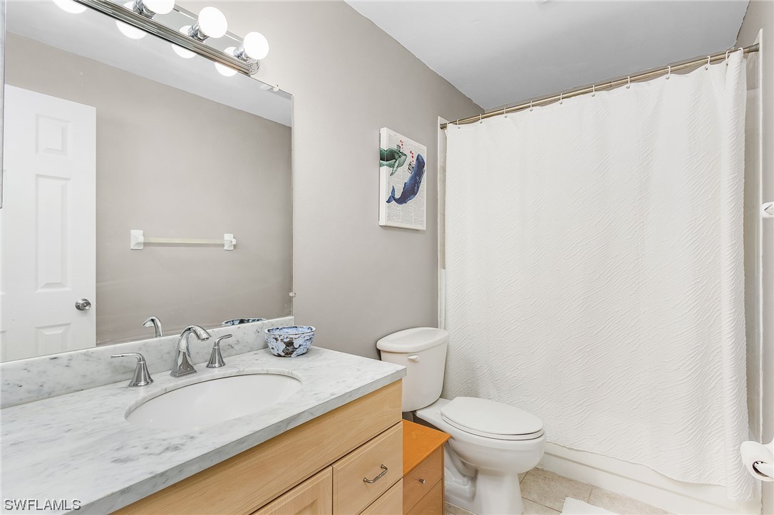 5791 Mackerel Road Bokeelia, FL 33922 - Photo 11 of 24 a bathroom with a granite countertop sink a toilet and a mirror