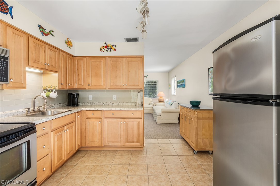 5791 Mackerel Road Bokeelia, FL 33922 - Photo 12 of 24 a kitchen with stainless steel appliances granite countertop a sink stove and cabinets