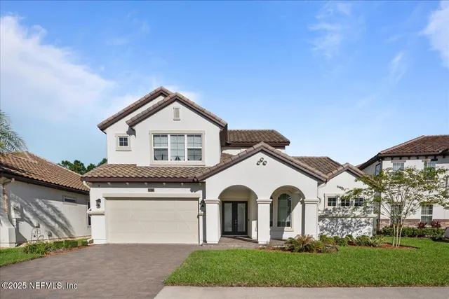 a view of a white house next to a yard and large trees