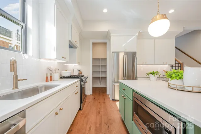 a kitchen with a sink a counter top space stainless steel appliances and cabinets