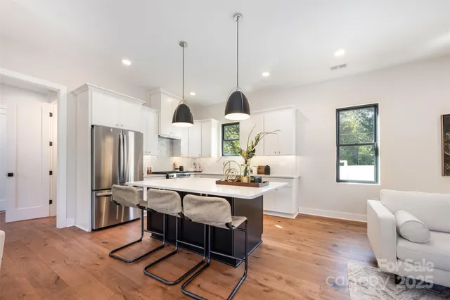 a kitchen with stainless steel appliances granite countertop a stove a sink a refrigerator a center island with a dining table and chairs