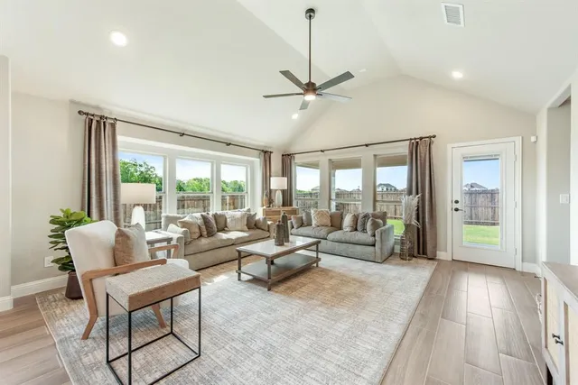 a living room with furniture large windows and wooden floor