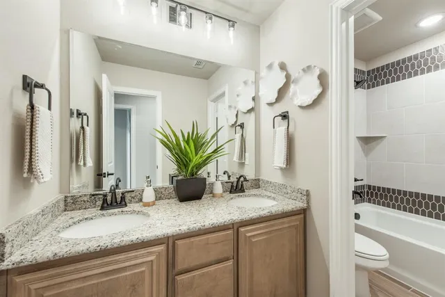 a bathroom with a granite countertop sink a toilet and a large mirror