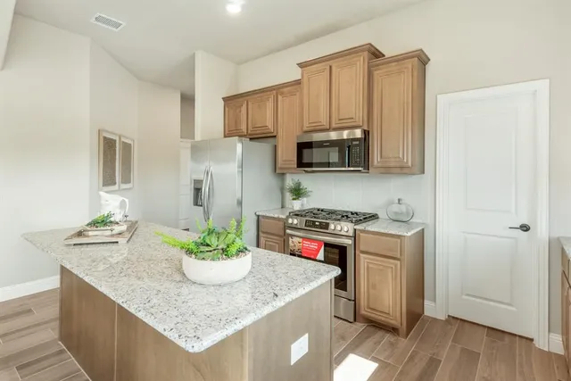 a kitchen with stainless steel appliances granite countertop a stove a refrigerator a sink a microwave and island