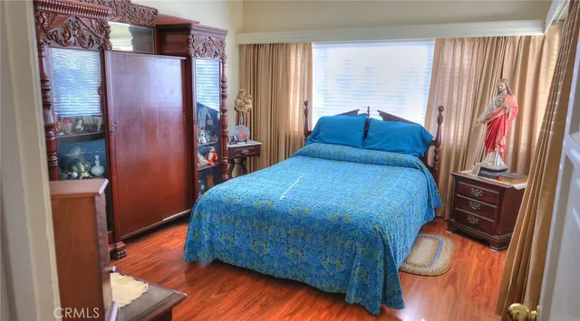 a bedroom with a large bed and wooden floor