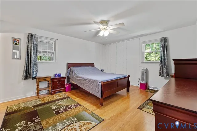 a bedroom with a bed and a dresser with wooden floor