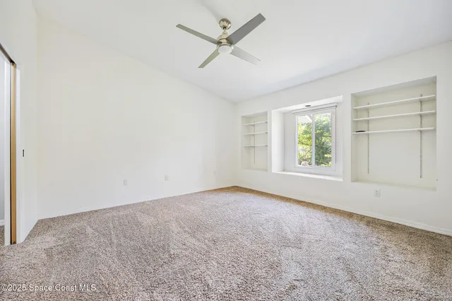 an empty room with a window and a fan