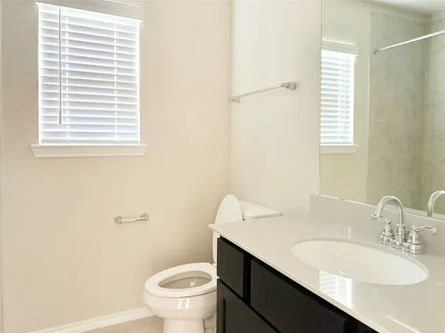 a bathroom with a granite countertop sink toilet and a mirror
