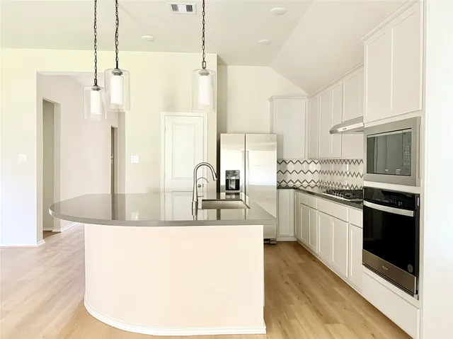 a kitchen with stainless steel appliances granite countertop a sink a stove and a refrigerator