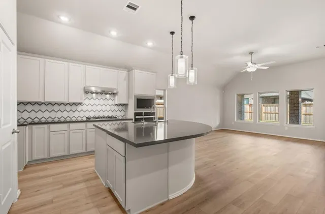 a kitchen with stainless steel appliances granite countertop a sink a stove and a wooden floors