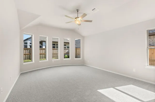 an empty room with windows and ceiling fan