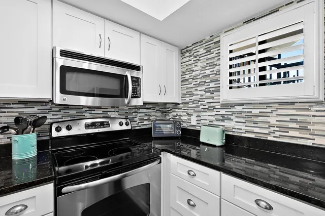 a kitchen with stainless steel appliances a refrigerator a microwave a stove and a dining table with wooden floor