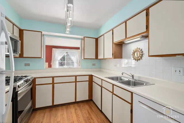 a kitchen with a sink cabinets stainless steel appliances and a window