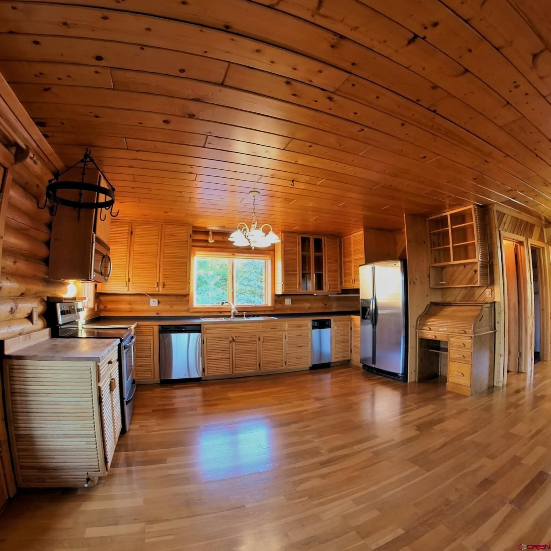 24119 Ute Trail Road Cedaredge, CO 81413 - Photo 11 of 26 a large kitchen with stainless steel appliances wooden floors and table