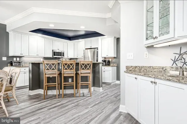 a kitchen with stainless steel appliances granite countertop a stove top oven a sink dishwasher and white cabinets next to a window