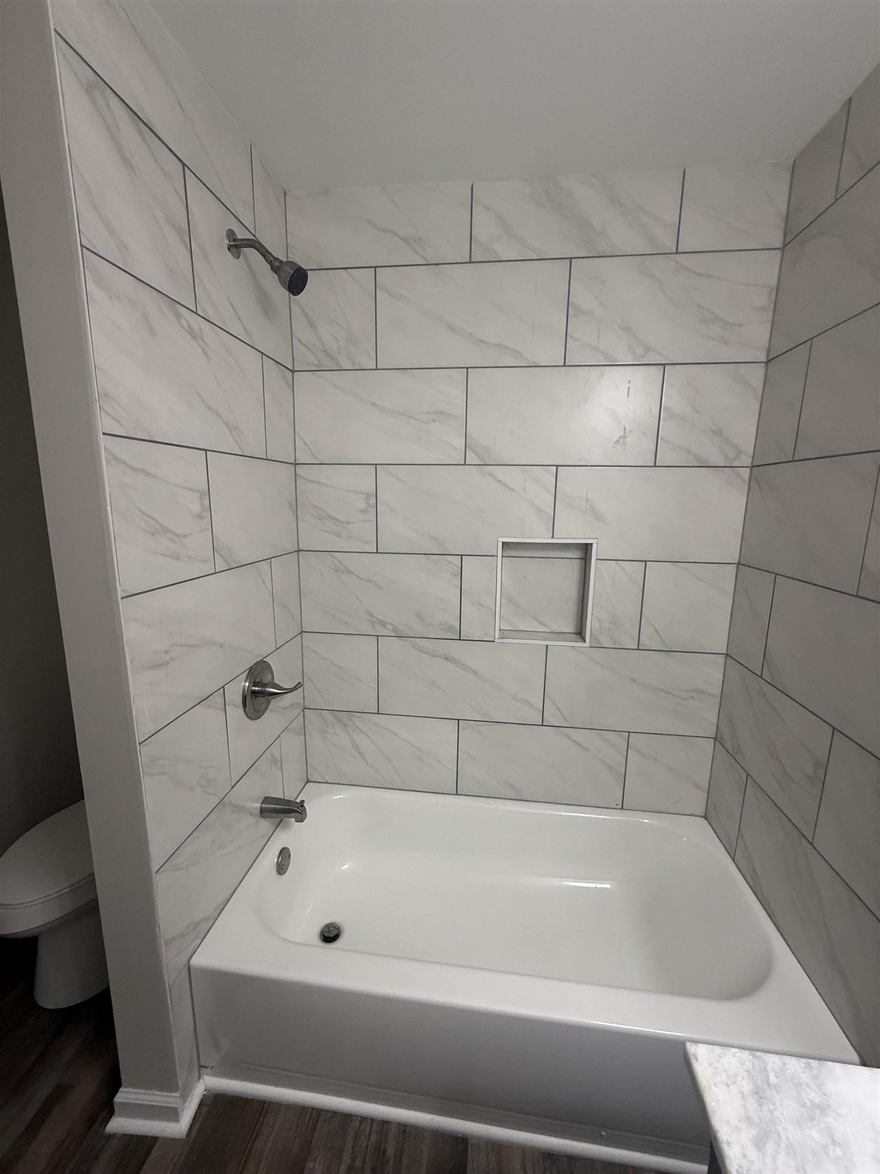 170 Leapwood Road Enville, TN 38332 - Photo 28 of 33 Tub and shower combination featuring a contemporary showerhead, white subway tile surround with gray veining, recessed niche, and polished chrome fixtures