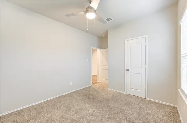 an empty room with closet and a chandelier fan
