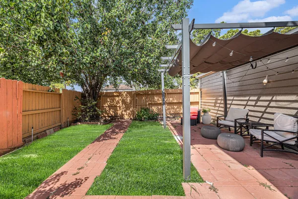 a view of a backyard with sitting area and tree