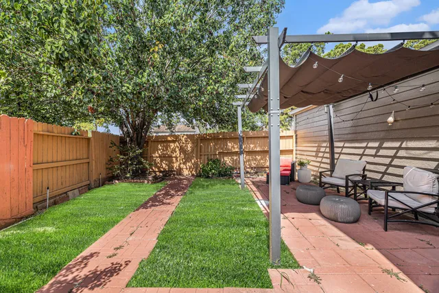 a view of a backyard with sitting area and tree