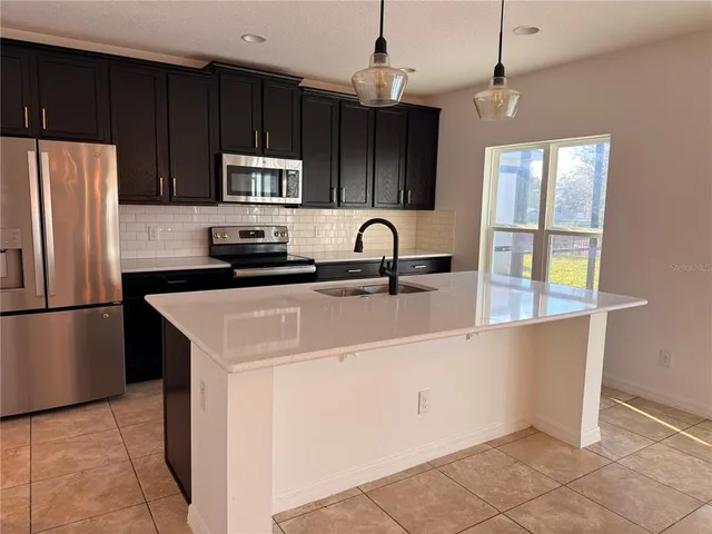 a kitchen with stainless steel appliances a refrigerator a sink a stove a microwave and island