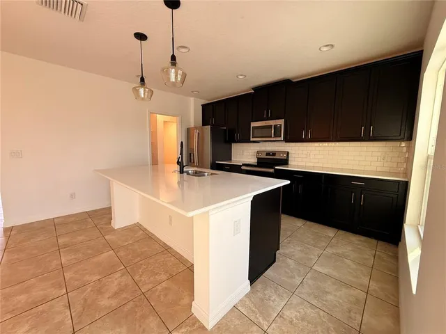 a kitchen with stainless steel appliances a sink a stove a microwave a center island and cabinets