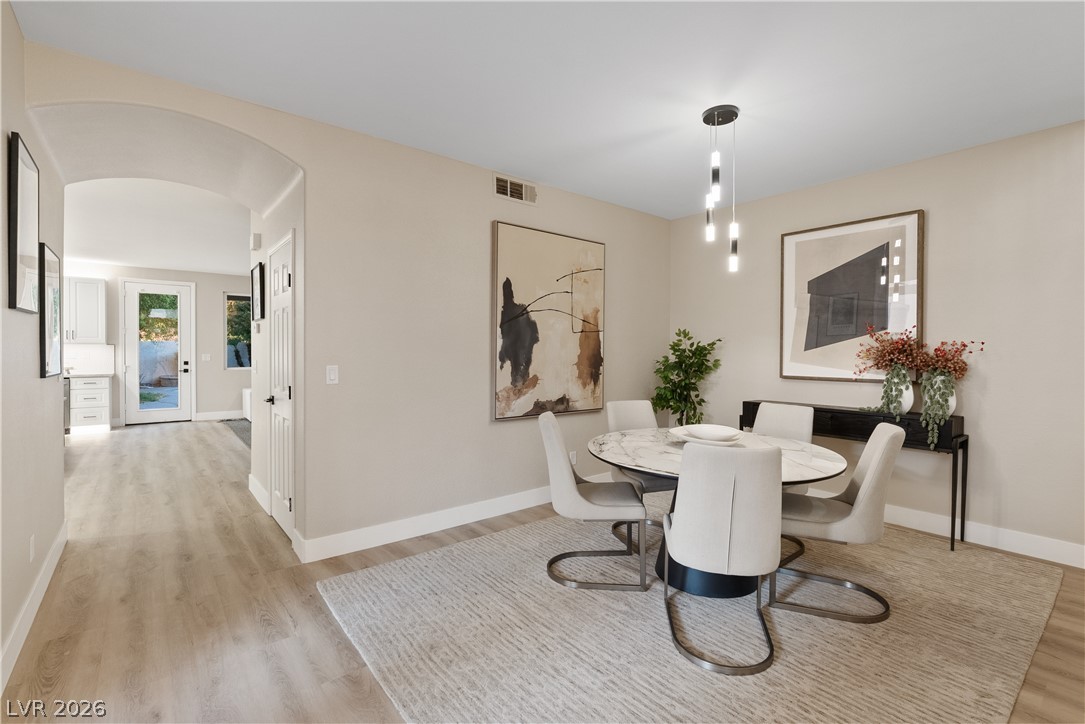 1662 Ravanusa Drive Henderson, NV 89052 - Photo 49 of 74 A well-lit dining area features a modern chandelier and light wood flooring leading to an arched entry.
