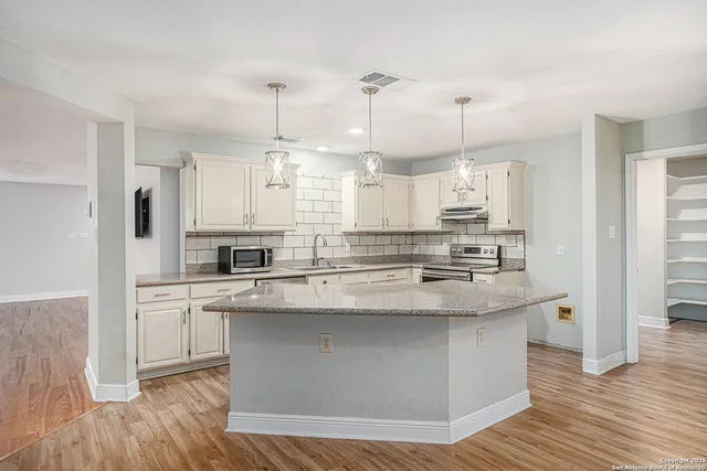 a kitchen with stainless steel appliances granite countertop a sink a stove and a refrigerator
