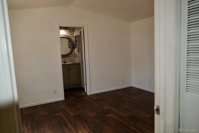 an empty room with wooden floor mirror and closet