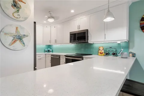 a kitchen with kitchen island granite countertop a stove a sink and a microwave