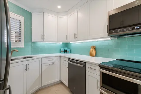 a kitchen with white cabinets and black appliances