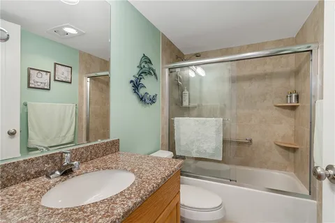 a bathroom with a granite countertop sink toilet and shower