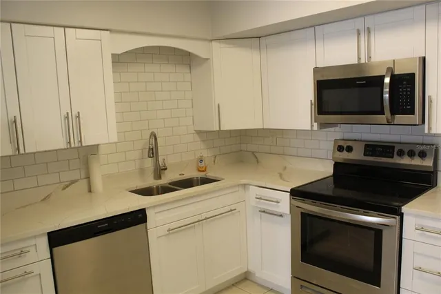 a kitchen with stainless steel appliances a stove microwave and sink
