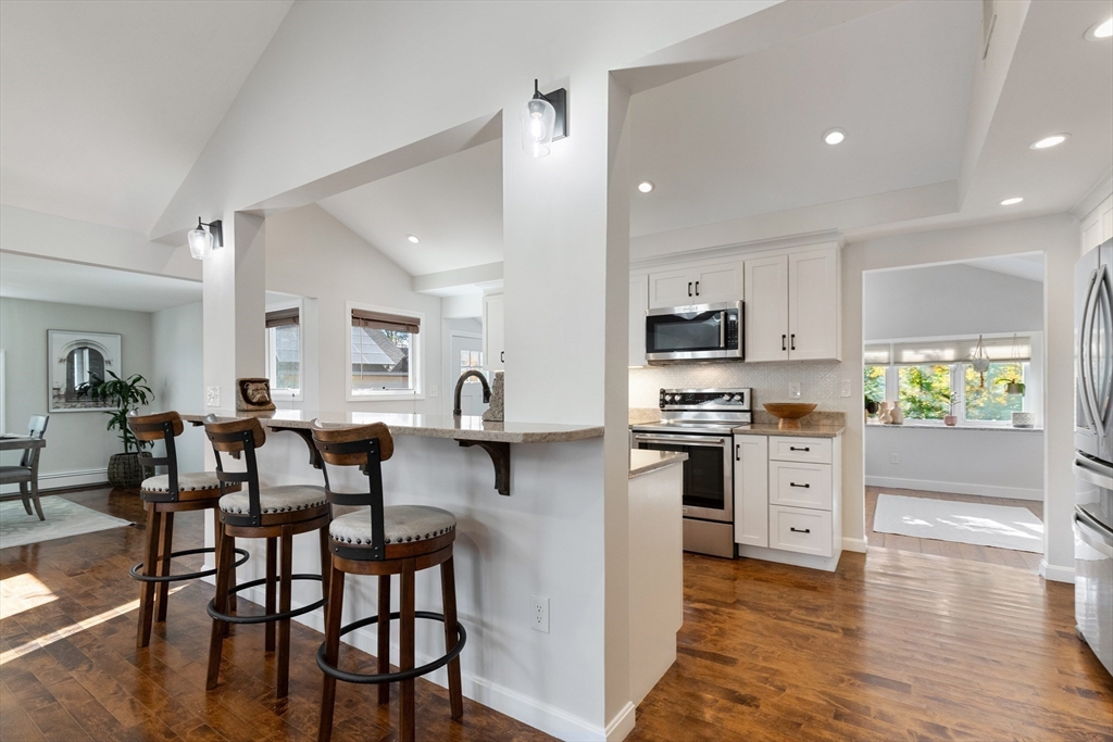 4 Senator Road Woburn, MA 01801 - Photo 6 of 36 a kitchen with stainless steel appliances granite countertop a stove top oven a sink dishwasher and a dining table with wooden floor
