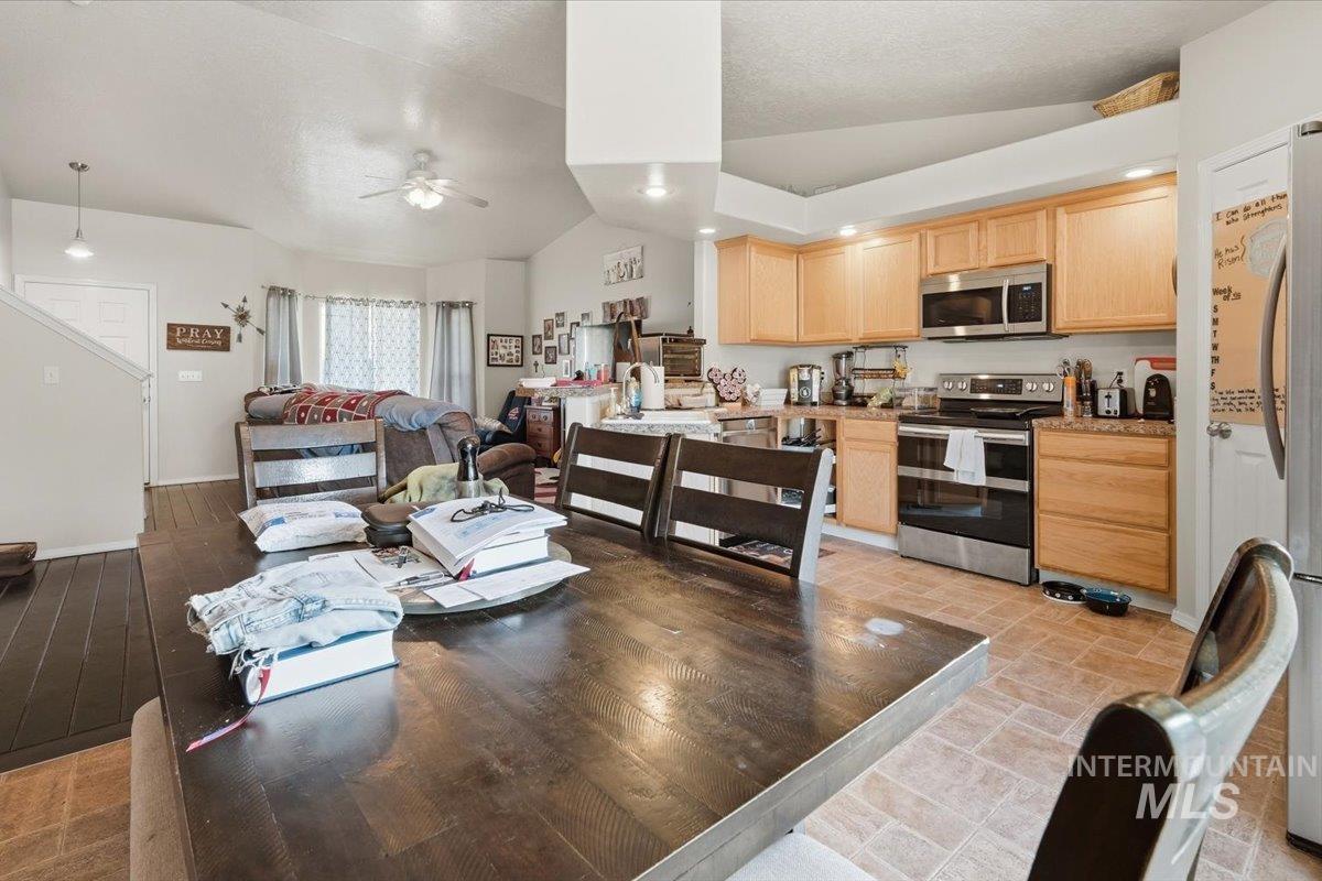 2714 Colfax Drive Caldwell, ID 83607 - Photo 11 of 40 Open-concept kitchen and living area featuring stainless steel appliances, light wood-finish cabinetry, and a dining area with wood-finish flooring